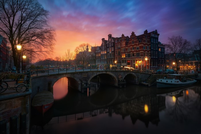 Amsterdam canal bridge at sunset with historic buildings