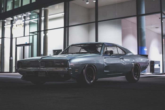Silver Dodge Charger parked in front of a modern building