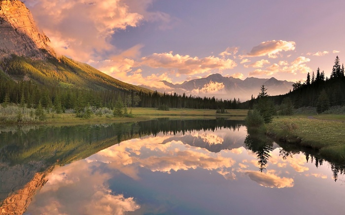 Mountain lake reflection at sunset with clouds