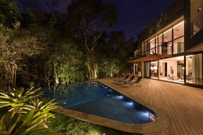 Modern house with swimming pool and trees at night