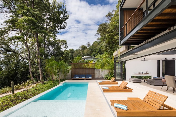 Modern house with swimming pool and lounge chairs in a tropical setting