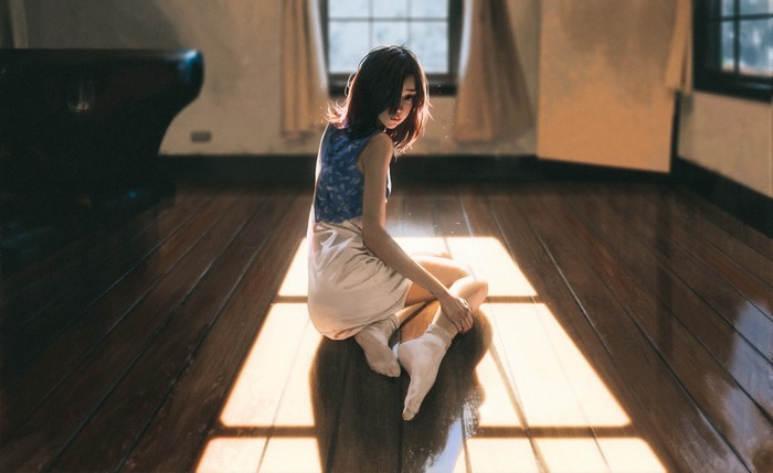 Woman sitting on wooden floor by window