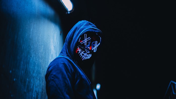 Man in a blue hoodie wearing a glowing mask