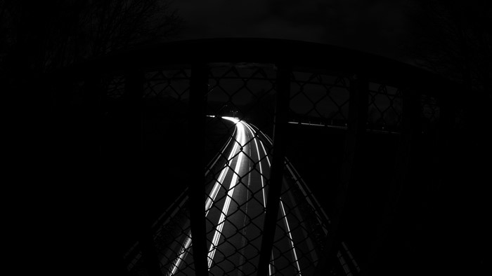 Long exposure of a highway at night through a fence