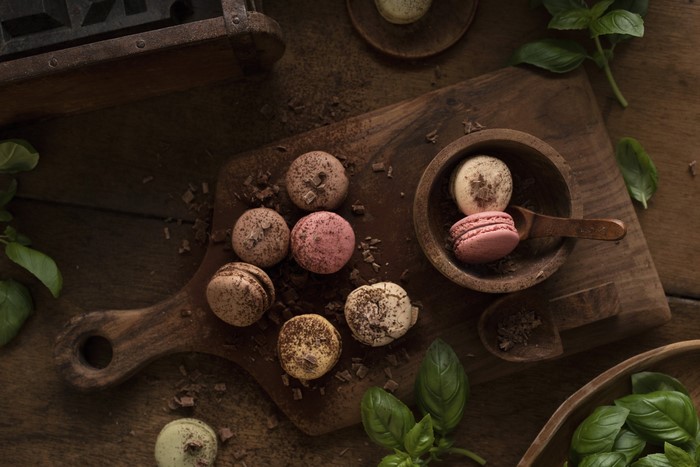 Macarons with chocolate shavings and basil on a wooden board