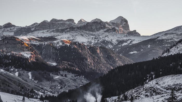 Snow-covered mountains with pine trees and a village