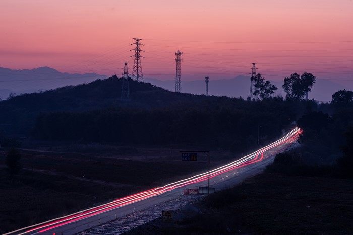 Light trails on a road with power lines at dusk