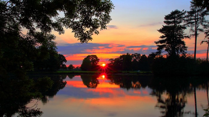 Sunset over a lake with trees and reflections