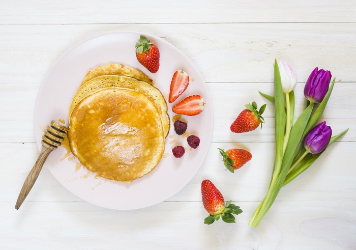 Pancakes with strawberries, raspberries, honey, and tulips