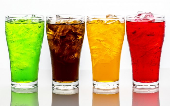 Four colorful drinks with ice in glasses