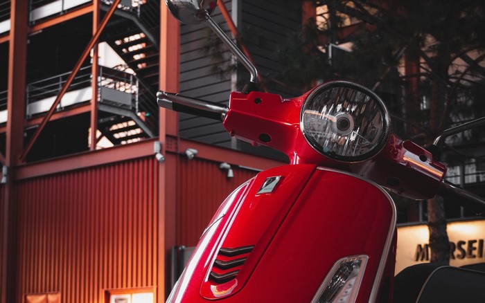 Red scooter parked near a modern building