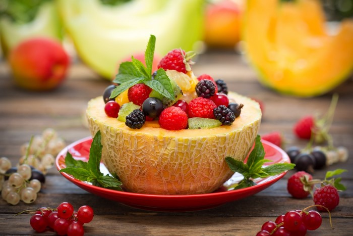 Fruit salad in a melon bowl with berries and mint