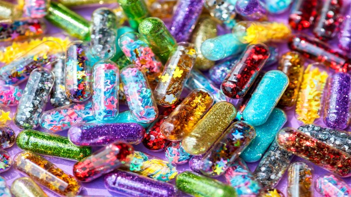 Colorful glitter-filled capsules on a purple background