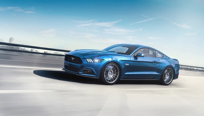 Blue Ford Mustang GT 5.0 driving on a highway