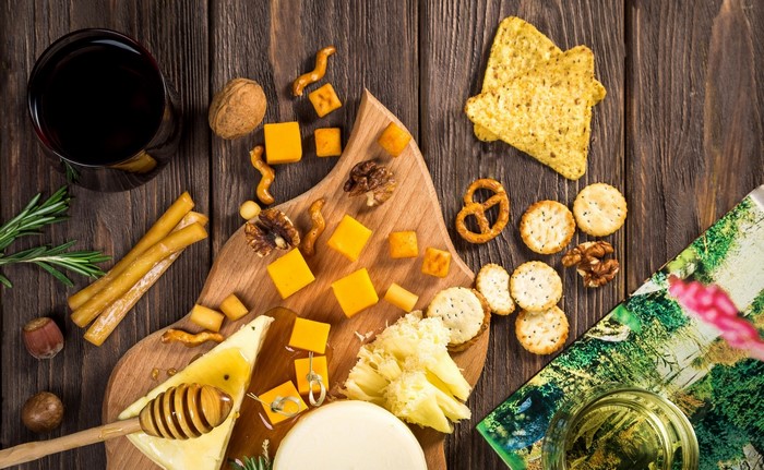 Cheese board with wine, nuts, crackers, and honey