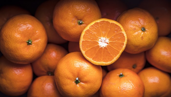 Close-up of fresh oranges, one sliced in half