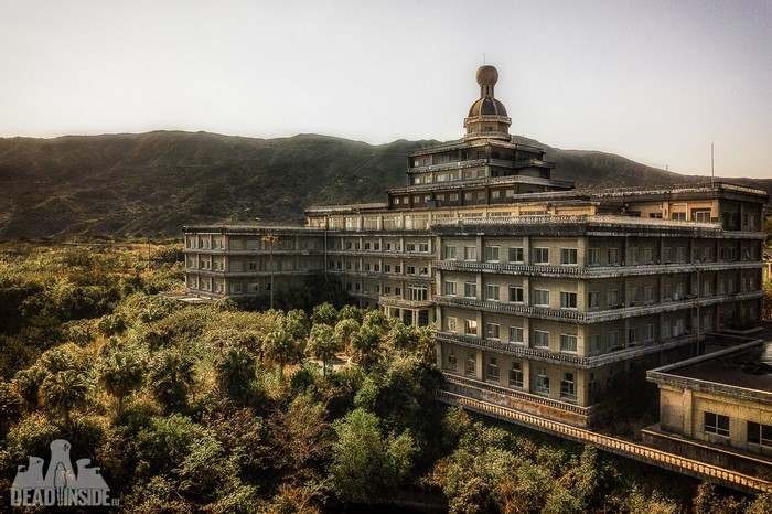 Abandoned building with dome in overgrown landscape