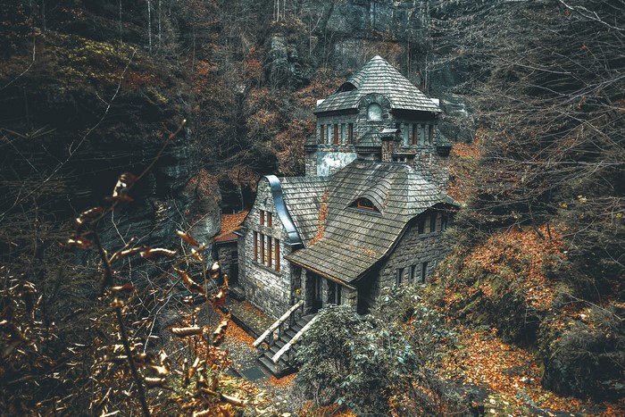 Stone house in a forest with fallen leaves
