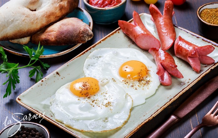 Fried eggs and sausages with bread and sauce