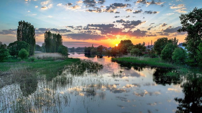 River landscape at sunset with trees and clouds