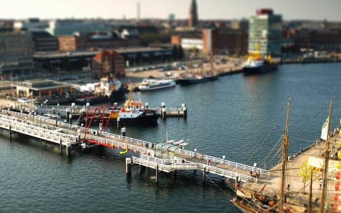 Tilt shift view of a harbor with tug boats and sailing ships