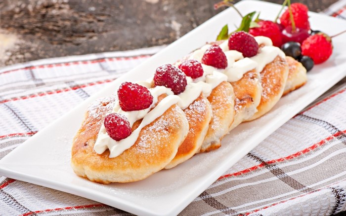Pancakes with cream and berries on a white plate