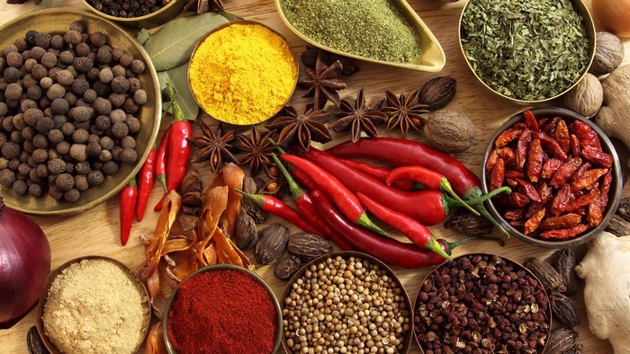 Assortment of spices including black pepper, chili peppers, and turmeric