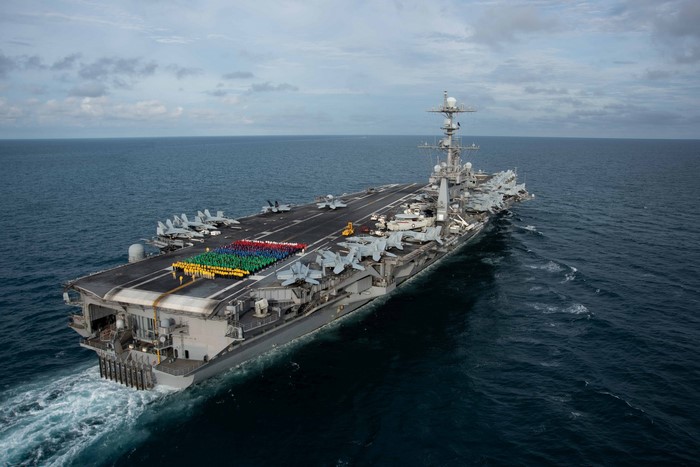 US Navy aircraft carrier with fighter jets and crew