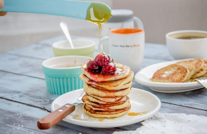 Stack of pancakes with cherries and honey