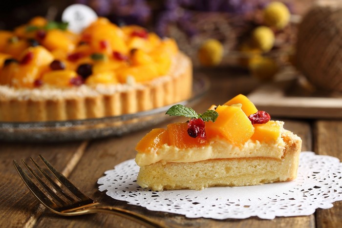 Slice of fruit tart with whole tart in background