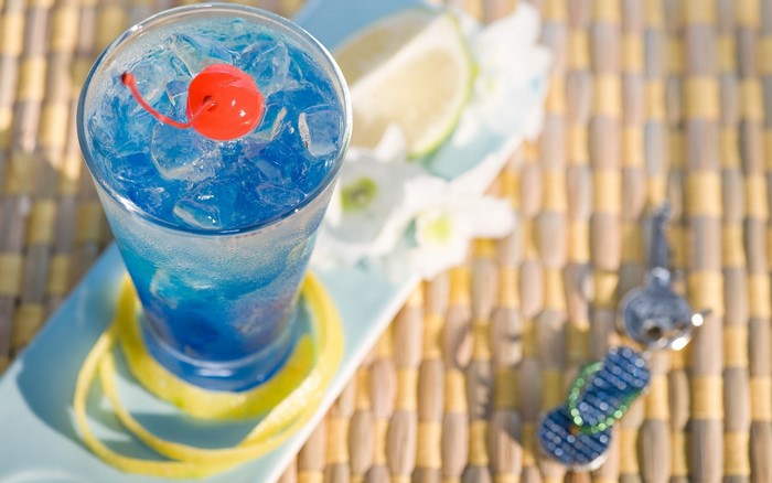 Blue cocktail with cherry and lime on a tray
