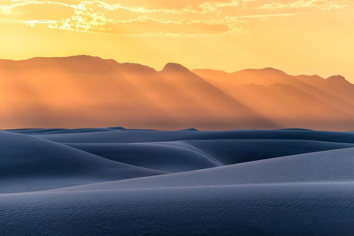 Sunset over desert dunes with sun rays