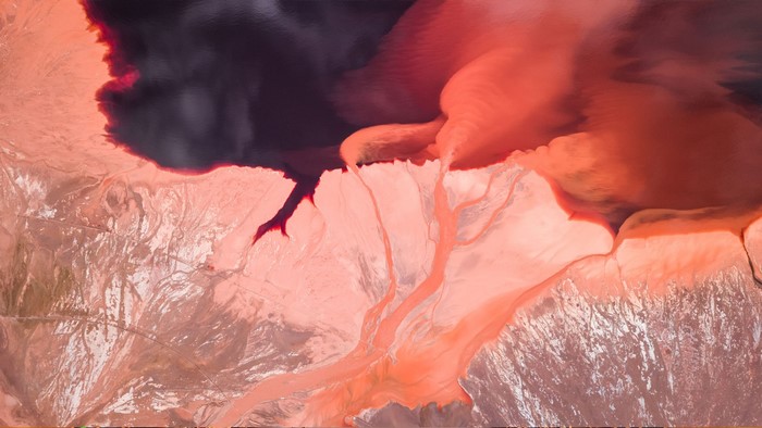Aerial view of red and dark water bodies with land formations