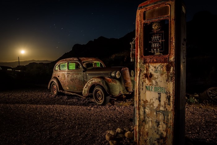 Old rusty car and gas pump at night