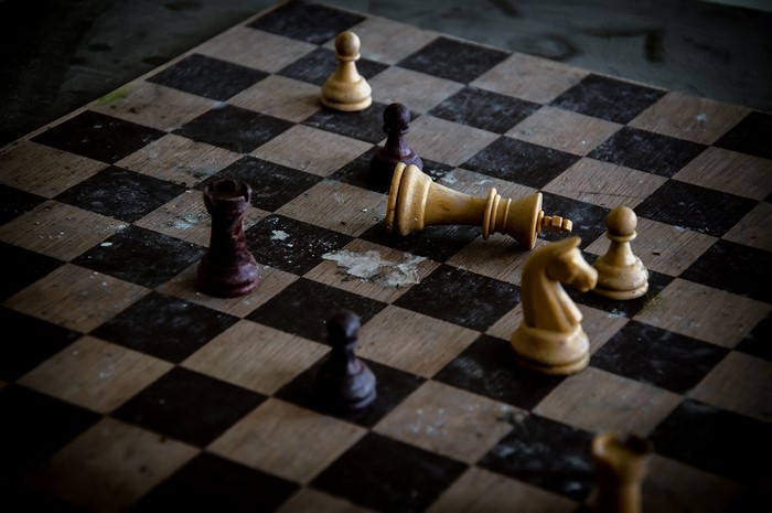 Chess board with fallen king and scattered pieces