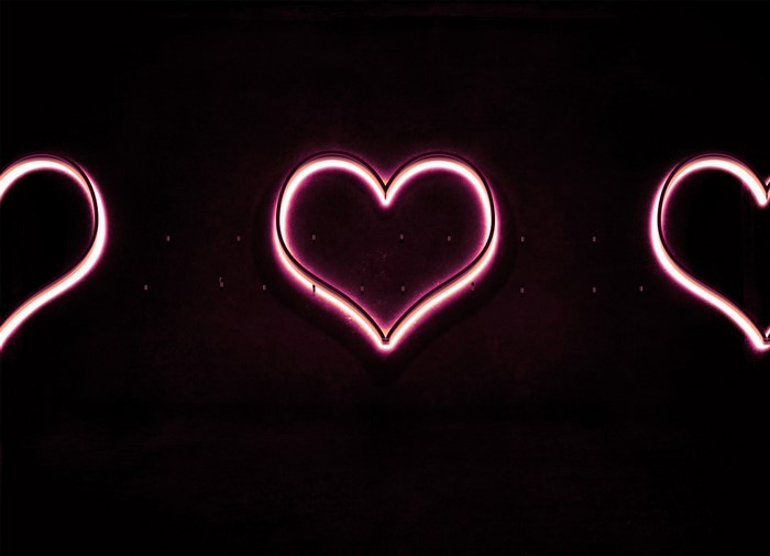 Three pink neon hearts on a dark background