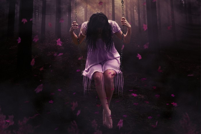 Girl on a swing in a dark forest