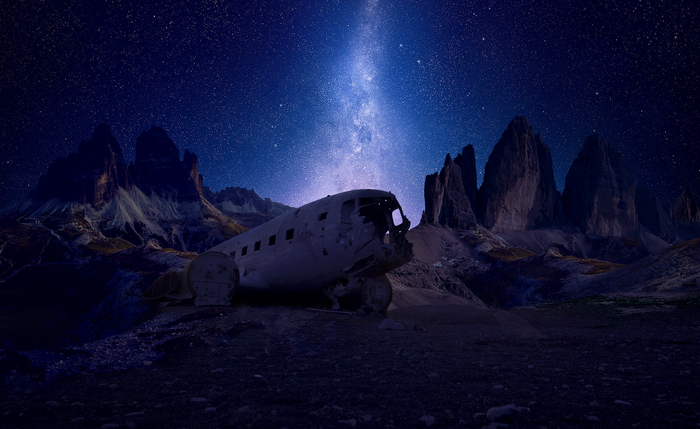 Airplane wreckage under the Milky Way in mountains