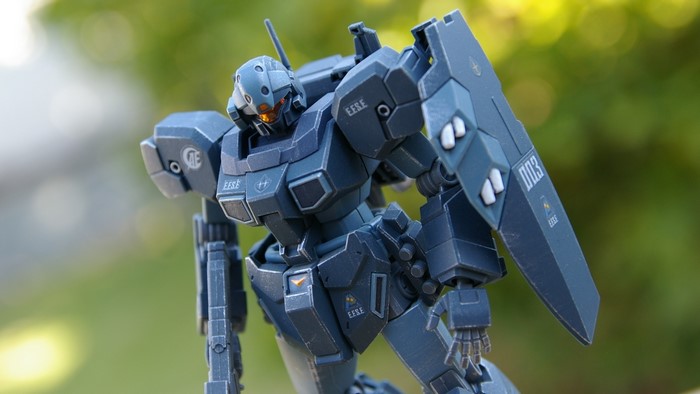 Gray Gundam model with shield and bokeh background