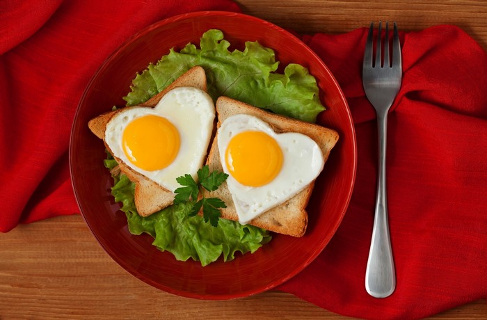 Heart-shaped eggs on toast with lettuce and fork