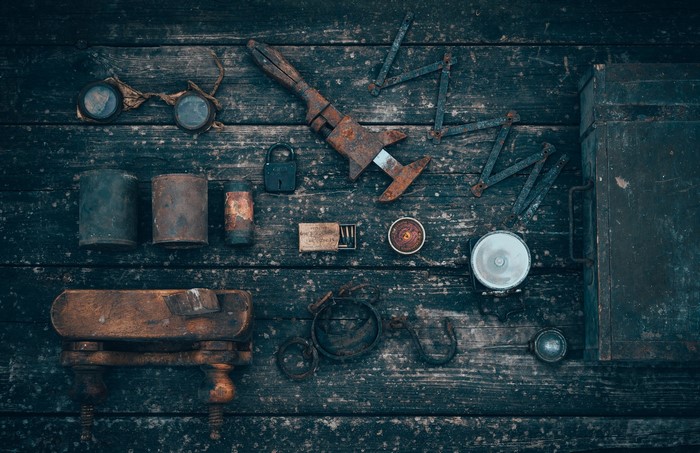Collection of old rusty tools and items on a wooden surface