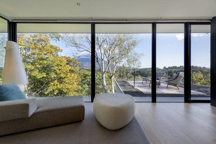 Modern living room with large windows overlooking a forest