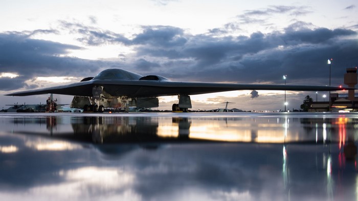 Northrop Grumman B-2 Spirit bomber on wet tarmac at dusk