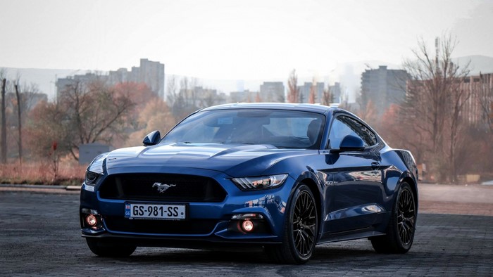 Blue Ford Mustang parked in front of buildings