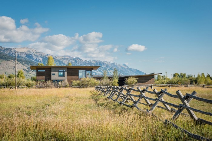 Modern house in a grassy field with mountains