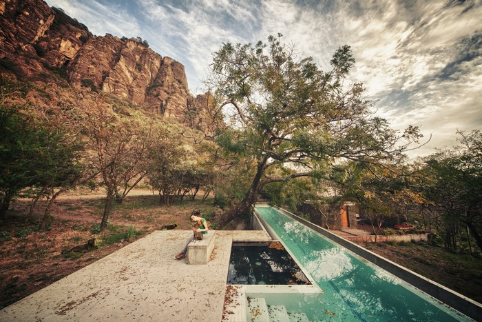 Woman sitting by a long swimming pool in a rocky landscape