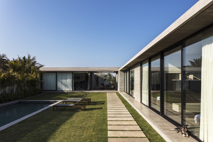 Modern concrete house with swimming pool and lounge chairs