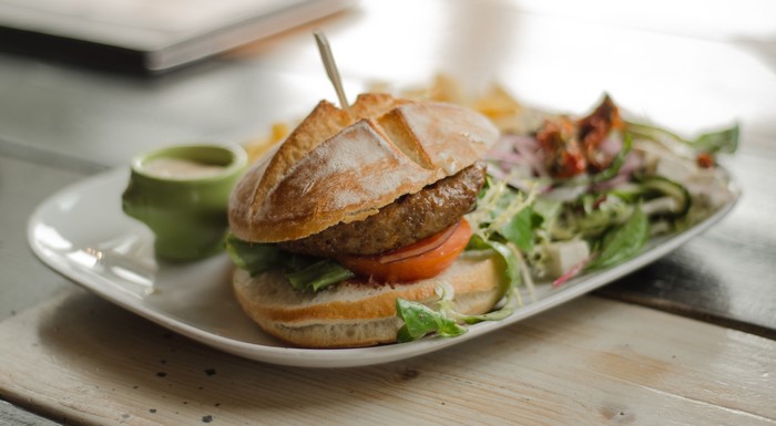 Burger with salad and fries on a wooden surface
