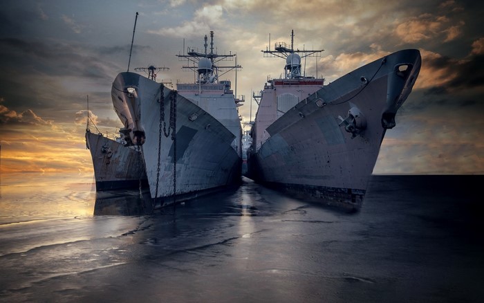 Two military ships docked at sea during sunset