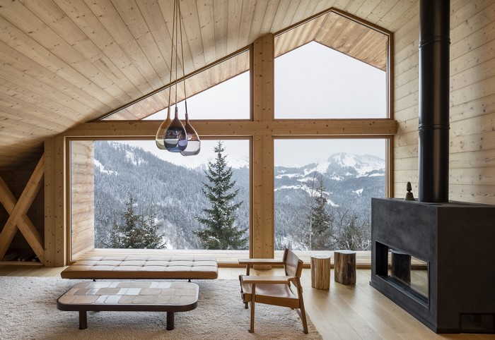 Cozy cabin interior with large windows overlooking snowy mountains